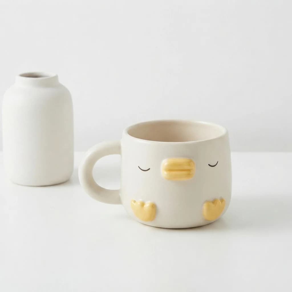 Duck-themed mug placed alongside a plain white vase to demonstrate scale on a desk.