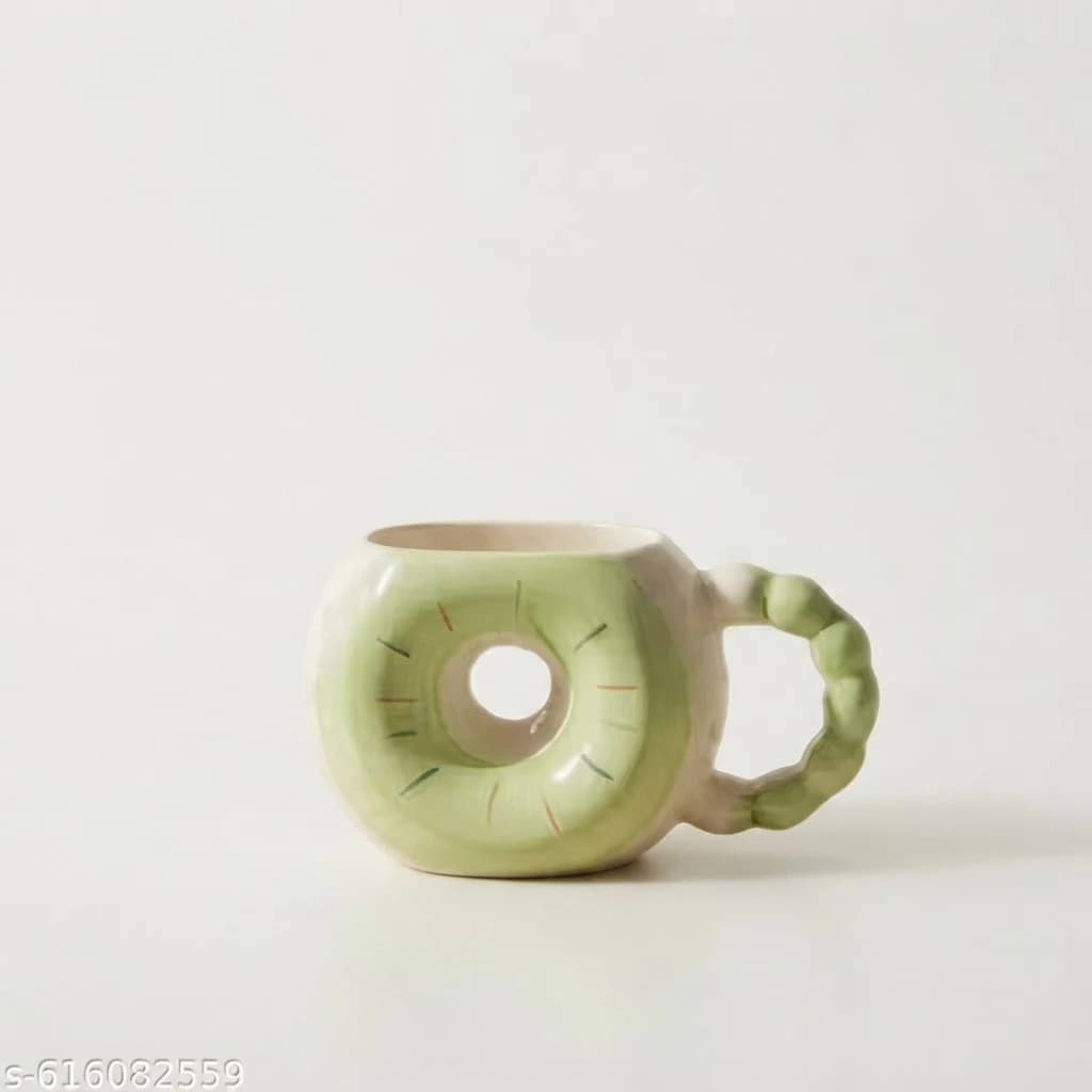 Green donut shape mug with central cutout hole and beaded handle on plain white surface