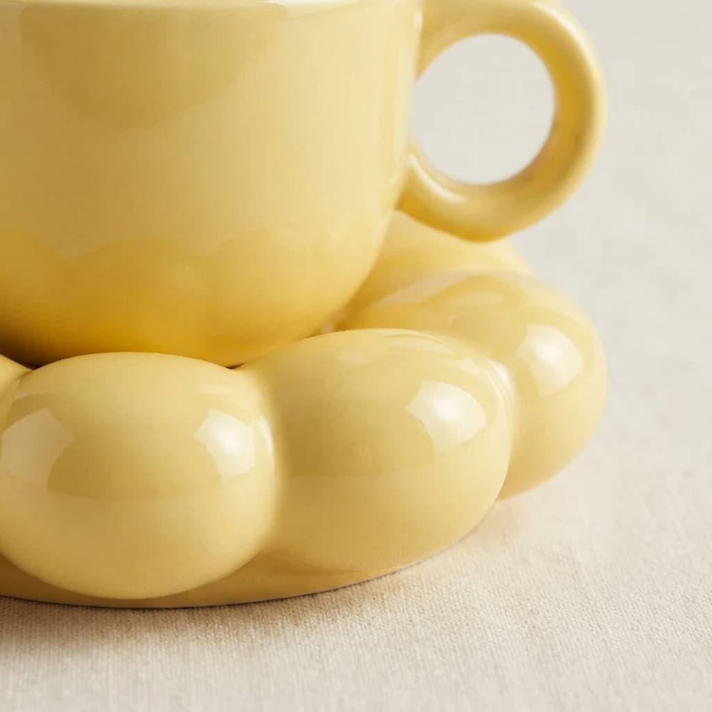 Close detail of the smooth petal rim on a glossy yellow flower saucer.